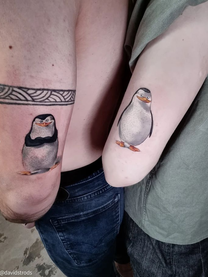 Side by side two penguin tattoos.